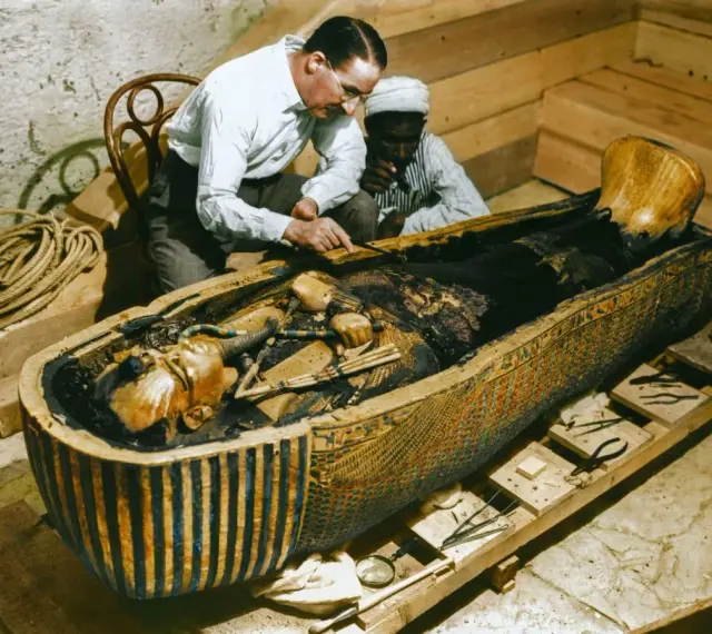 La photo découverte tombeau Toutankhamon : des archéologues examinent la momie dans son sarcophage orné.