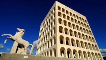 Le palais de la civilisation italienne, monument emblématique, se dresse fièrement sous un ciel bleu éclatant, avec une statue de cheval en avant-plan.